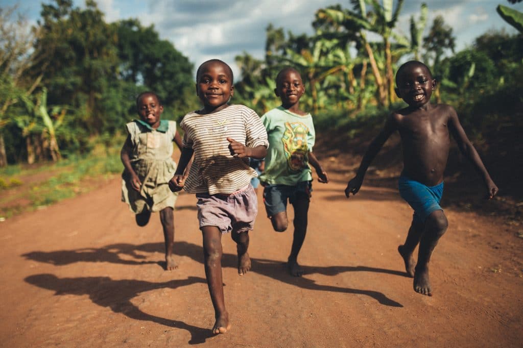 Children running joyfully on a rural road, reflecting hope and dignity in a developing community.