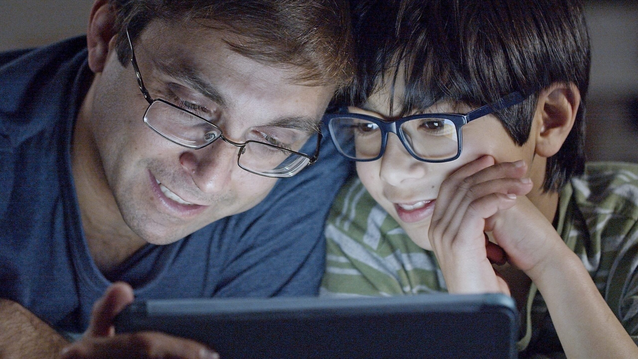 An image that with a boy and his dad looking at a tablet representing how to share the gospel on social media
